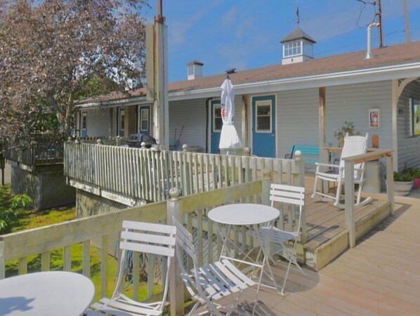A waterfront property with a deck, outdoor seating, and a covered area. - Dewar's Inn on the River (Augusta)