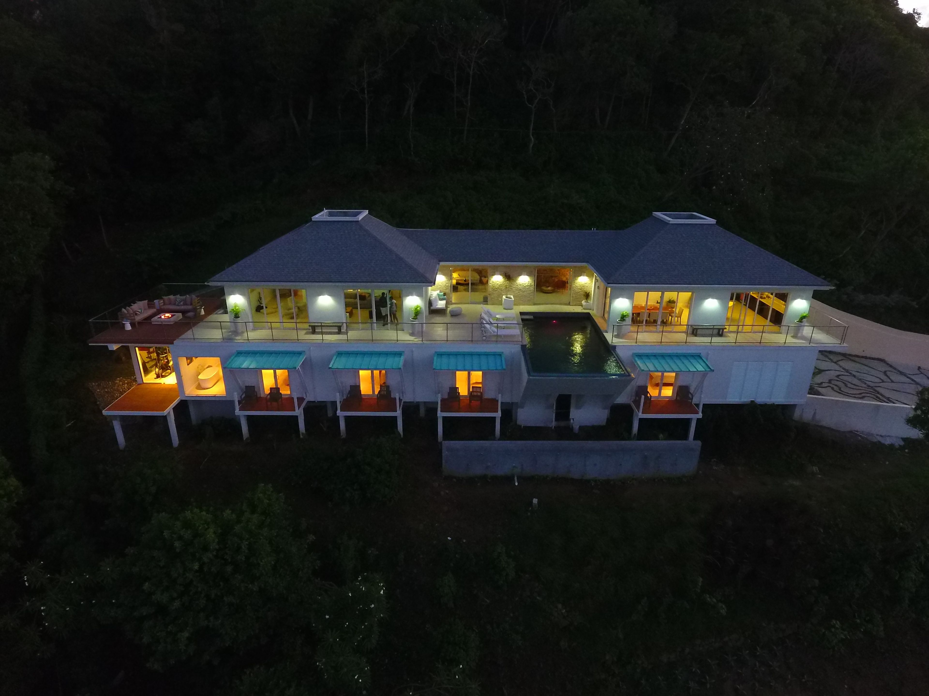 Ein modernes Haus mit mehreren Ebenen, Außenbereichen zum Sitzen und einem Swimmingpool.