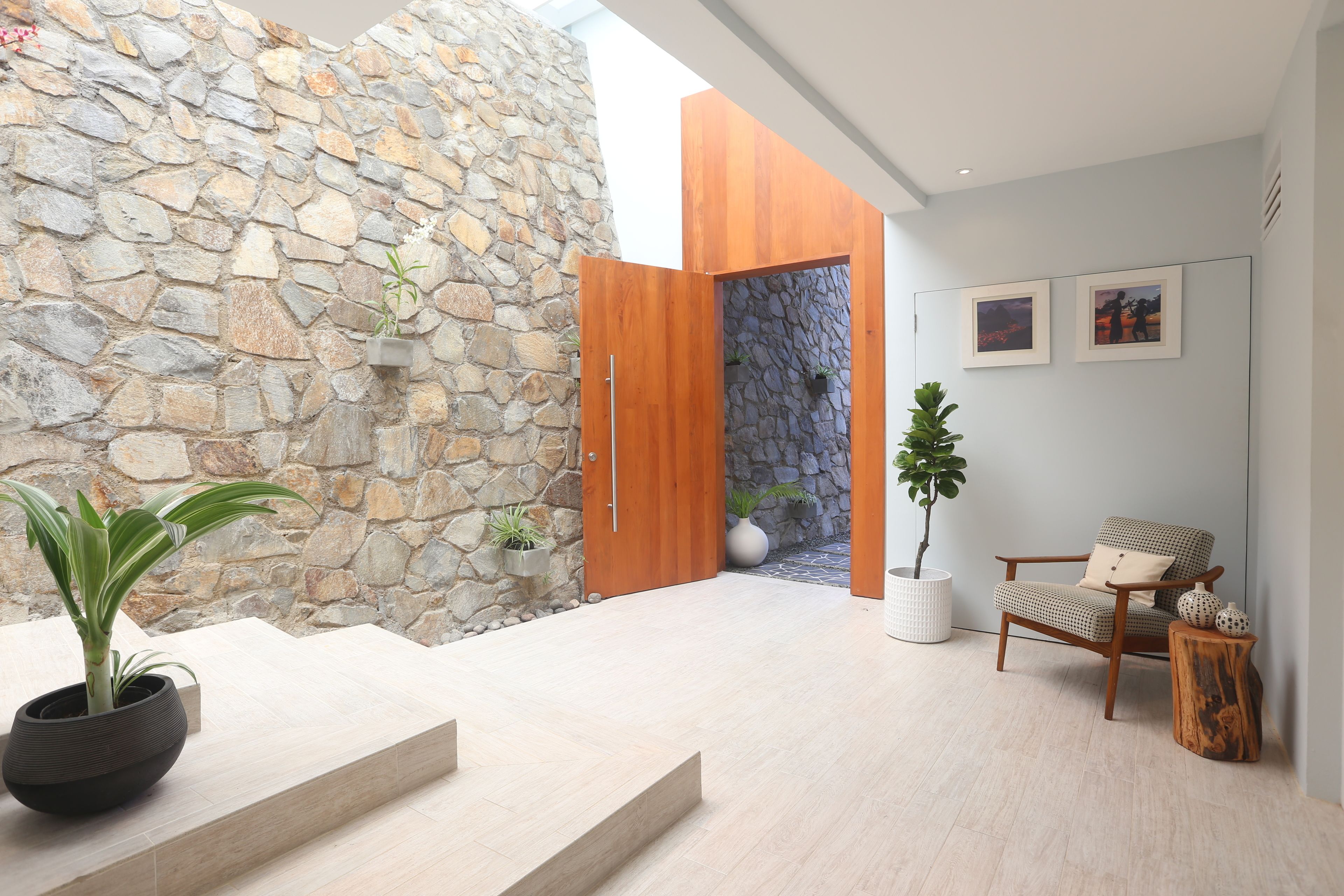 A modern interior with a stone wall, wooden door, and a seating area with a chair and a small table.
