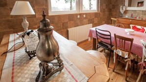 A cozy room with a wooden table, chairs, a lamp, and a decorative metal object.