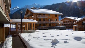 Eine Holzlodge mit mehreren Balkonen und verschneitem Gelände.