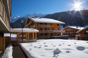 A wooden lodge with multiple balconies and a snow-covered ground. - Modern Alpine Apartment (La Clusaz)