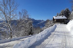 A snow-covered mountain road leading to a cabin with a clear sky. - Modern Alpine Apartment (La Clusaz)