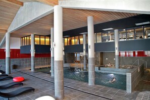 An indoor swimming pool with multiple levels, seating areas, and a sauna.