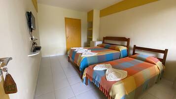 Habitación de hotel con dos camas, un televisor fijado a la pared, un refrigerador pequeño y una puerta que da a otra habitación.