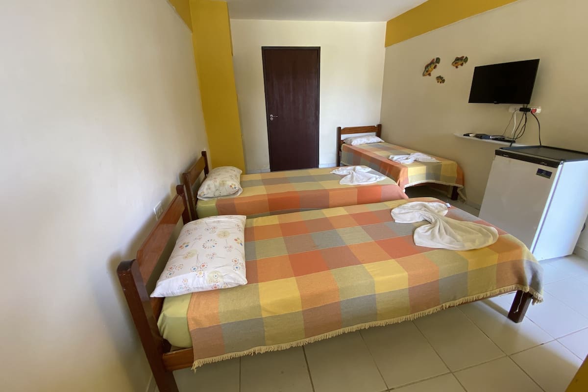 A hotel room with two beds, a television, and a refrigerator.