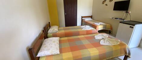 A hotel room with two beds, a television, and a refrigerator.