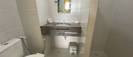 A small bathroom with a toilet, sink, and shower.