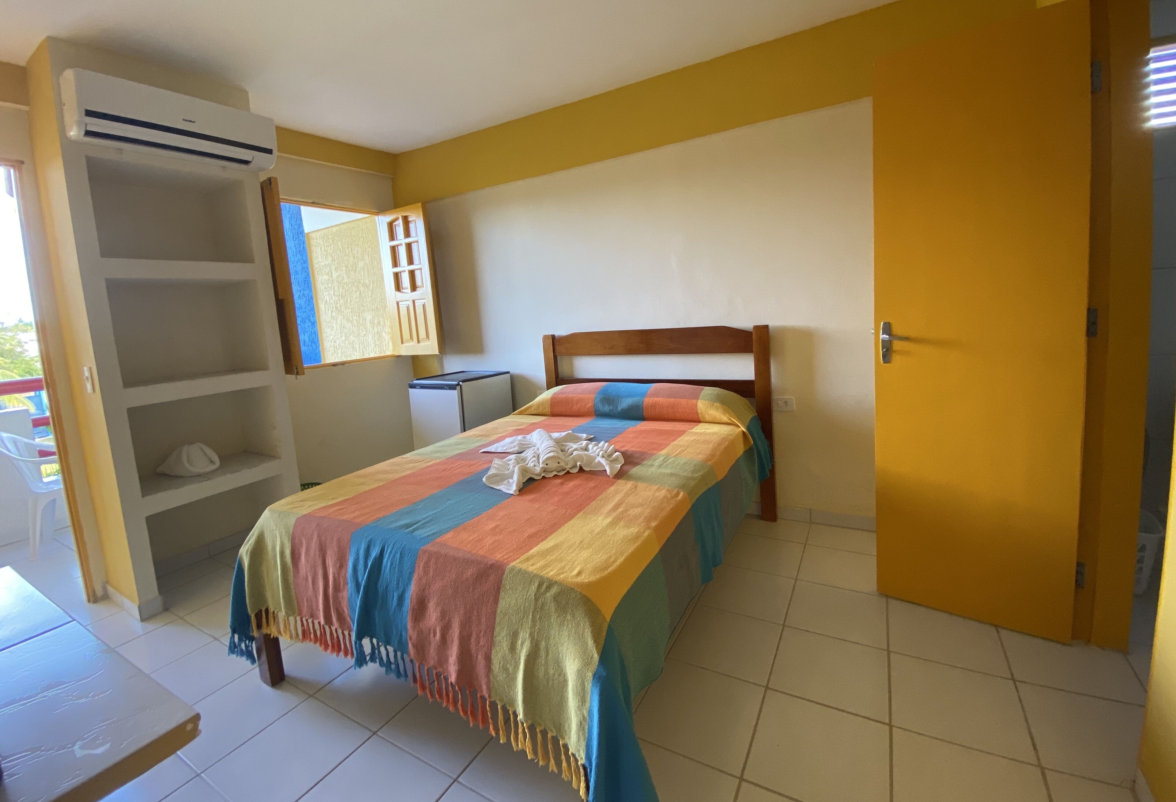Un dormitorio con cama, armario, escritorio y ventana.