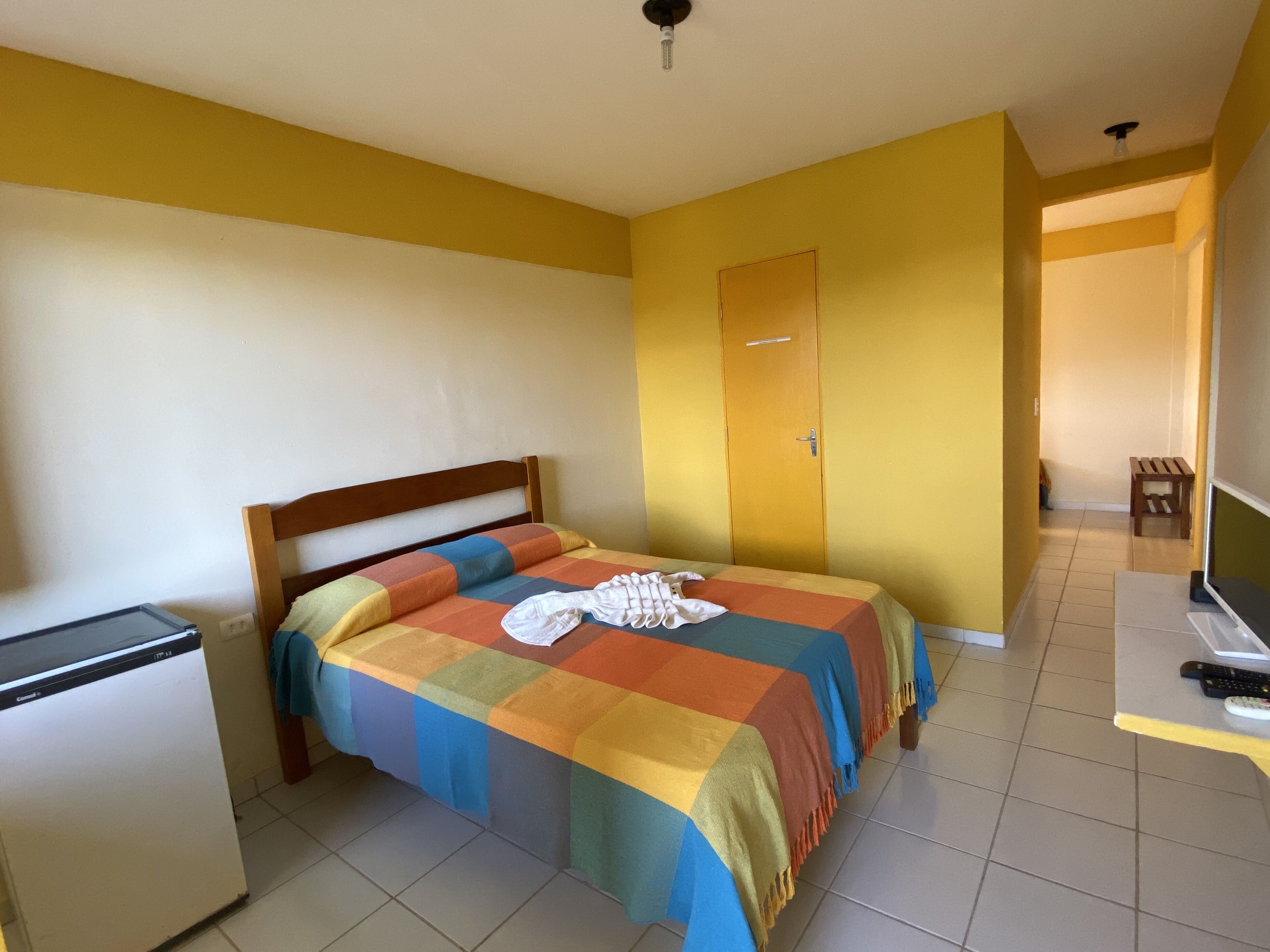 A room with a bed, a small desk with a laptop, and a door.