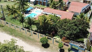 Vista aérea de un complejo turístico con varias construcciones, una piscina y abundante vegetación.