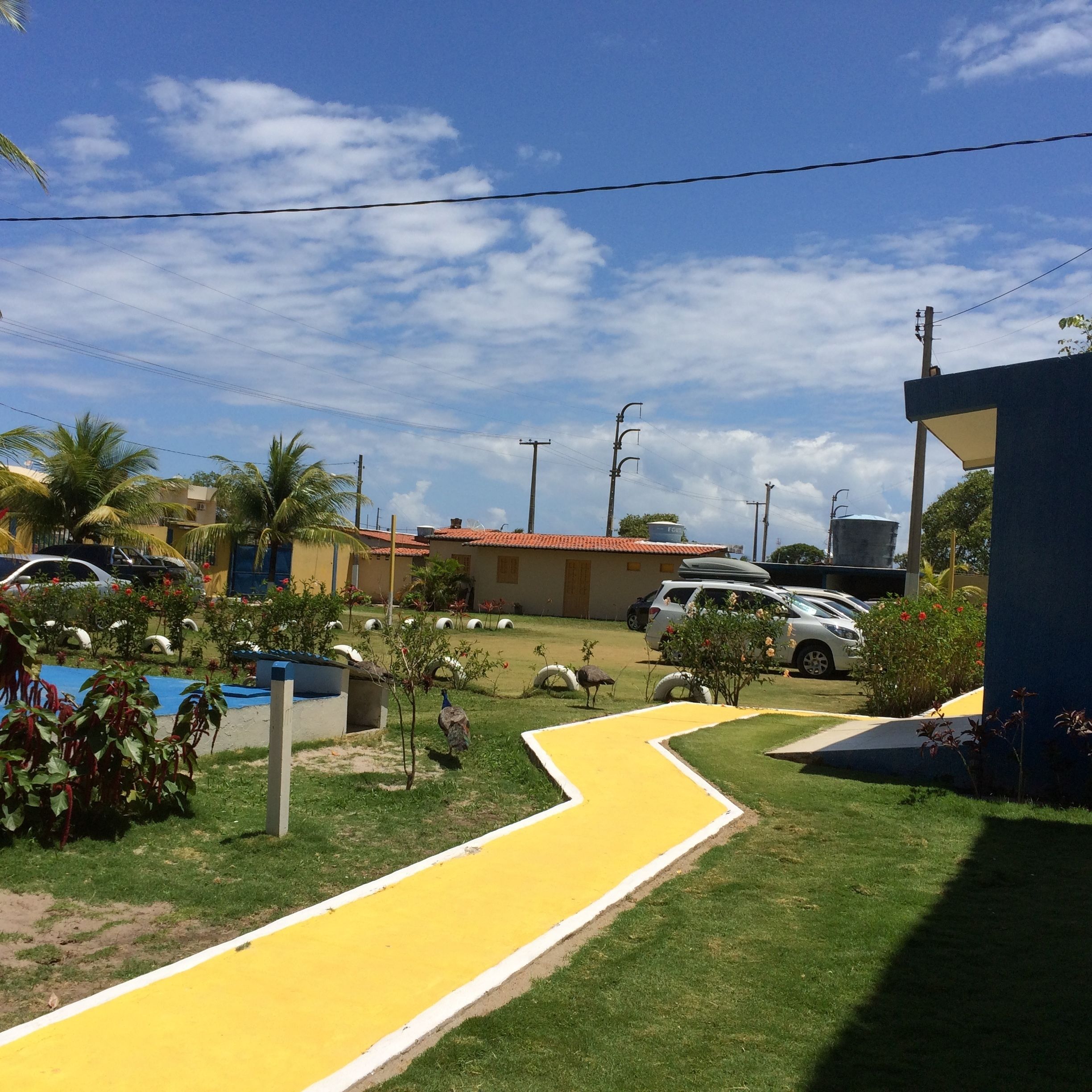Zona residencial con un sendero amarillo, coches aparcados y un edificio de techo rojo.