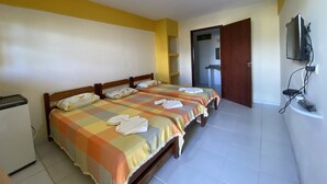 Una habitación de hotel con dos camas, un televisor montado en la pared y una puerta que da a un baño.