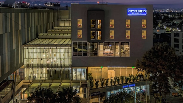 A modern hotel with a glass facade, a 'City Express by Marriott' sign, and a 'One Zone' store. - City Express by Marriott Ciudad De México La Raza (Mexico City)