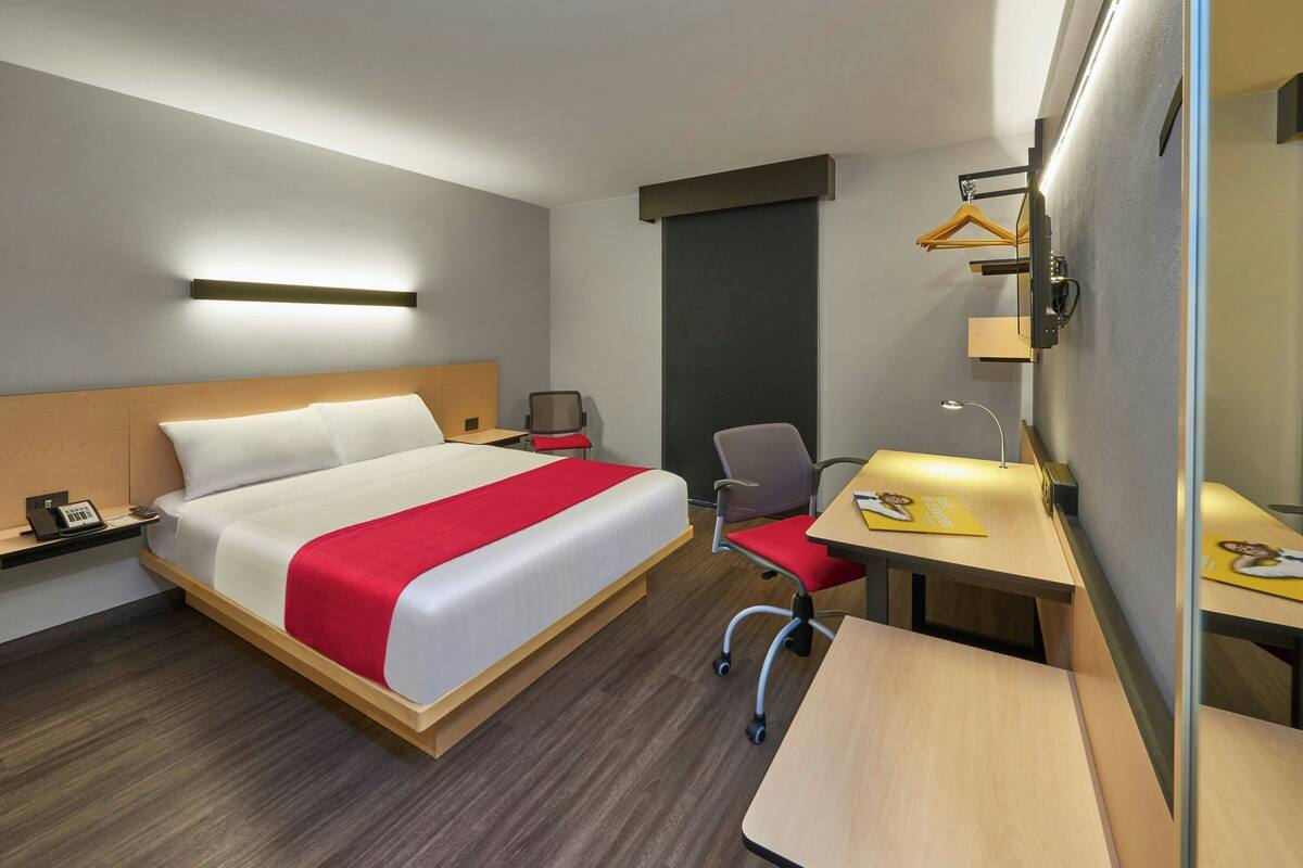 Hotellihuone, jossa on sänky, työpöytä, tuoli, puhelin ja lamppu.