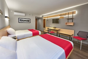 Two single beds with white bedding and red accents, a desk with chair, and a large mirror.