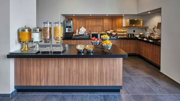 Een moderne keuken met een centraal eiland, voorzien van diverse voedseldispensers en een magnetron.