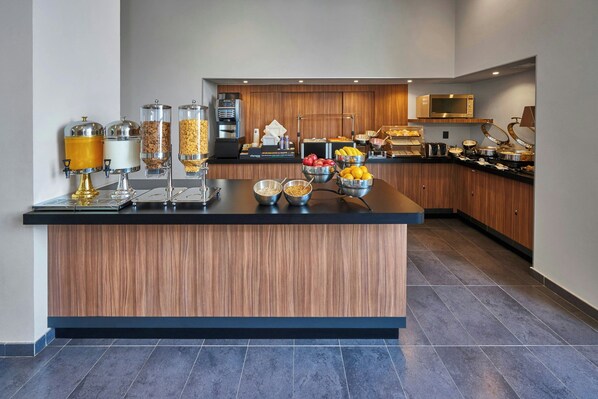 Una cocina moderna con una isla central, equipada con varios dispensadores de alimentos y un microondas.