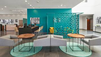 Een moderne hotellobby met een receptiebalie, een zithoek en decoratieve elementen.