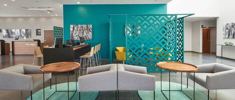 Un moderno vestíbulo de hotel con mostrador de recepción, zona de estar y detalles decorativos.