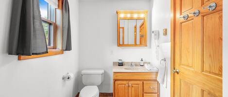 A compact bathroom with a toilet, vanity, and wooden cabinets.