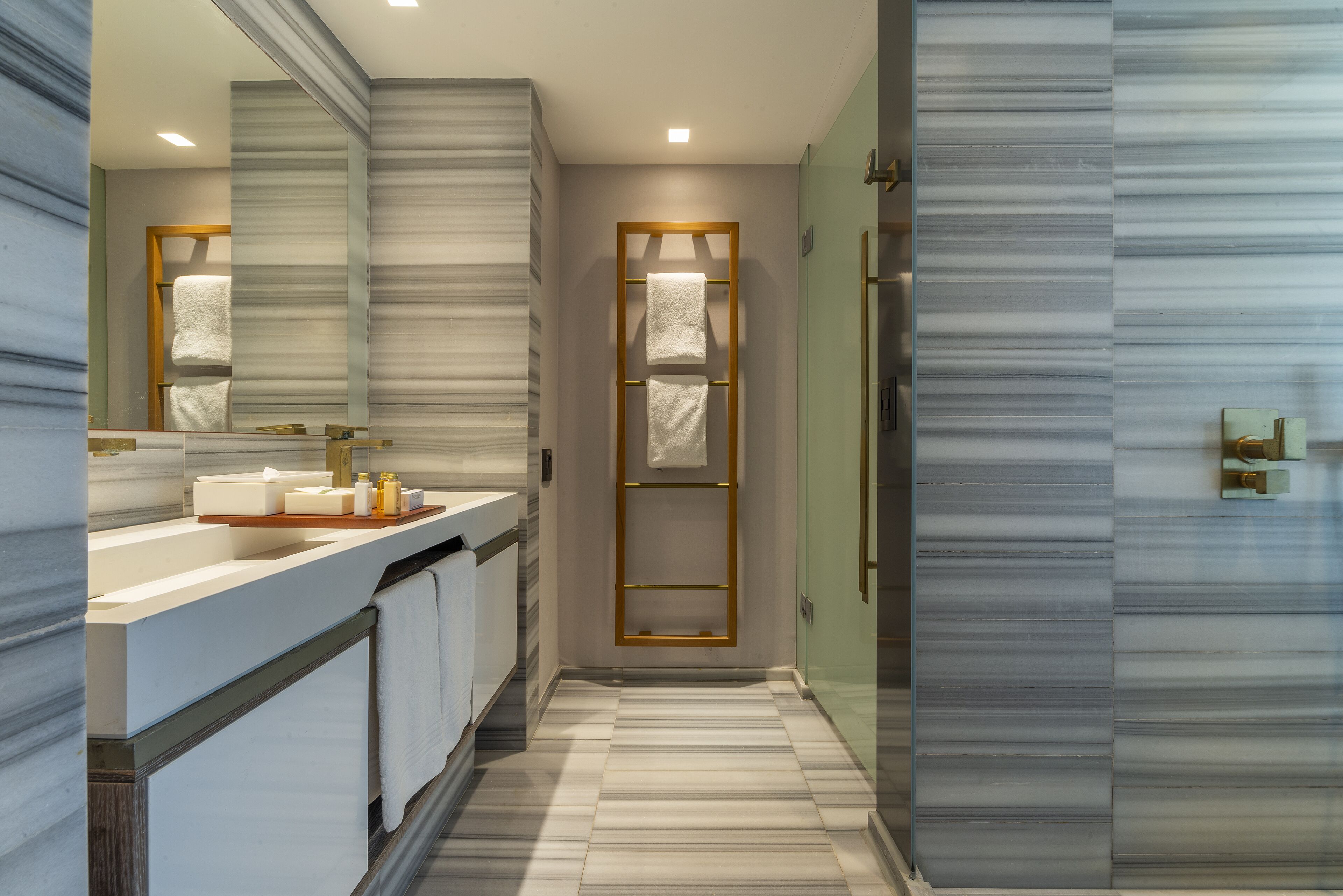 Un baño moderno con un espejo grande, un tocador con lavabo y un perchero para toallas.