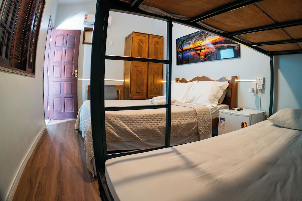 Ein Hotelzimmer mit zwei Betten, einem Holzschrank, einem Bild an der Wand und einem Nachttisch mit Lampe.