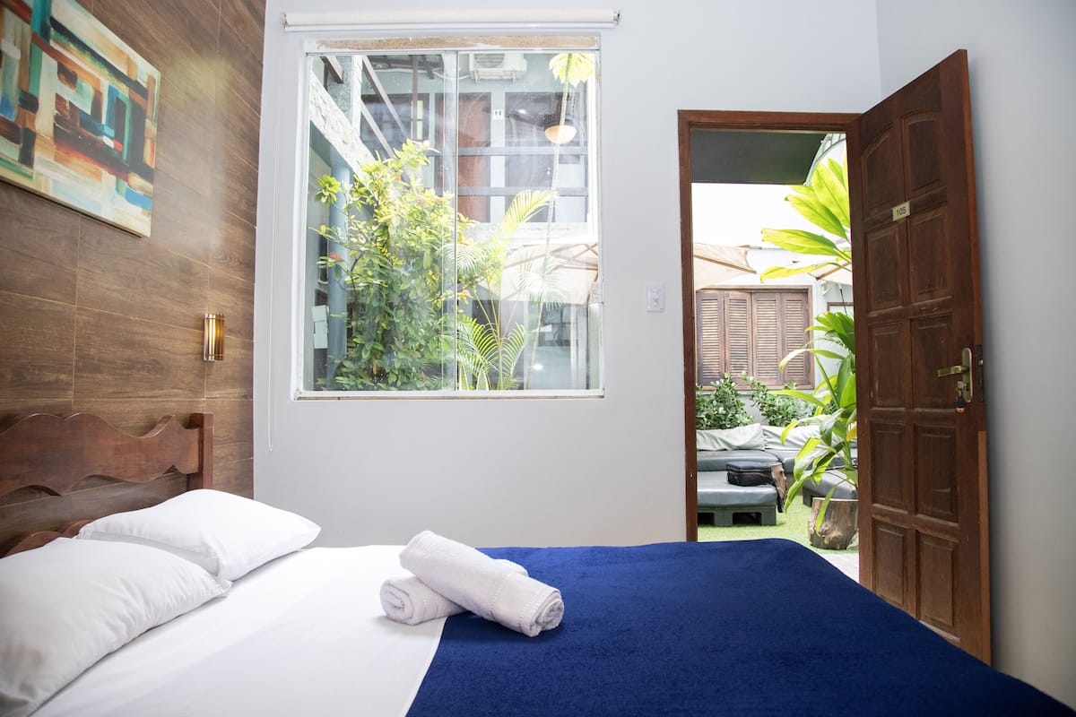 Ein Schlafzimmer mit Bett, Fenster und Ausblick nach draußen.