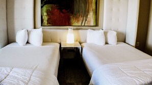 A hotel room with two beds, a nightstand with a lamp, and a large abstract painting on the wall. - Devonshire Inn (Rosamond)