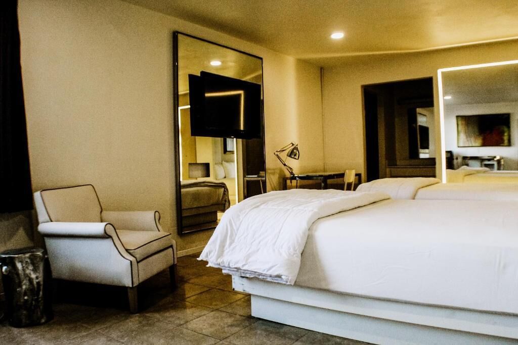 Una habitación de hotel con una cama, una silla, un escritorio y un espejo.