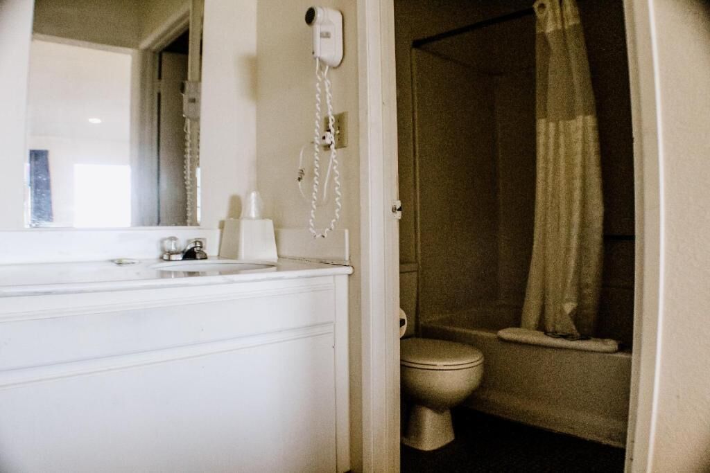 A bathroom with a toilet, a sink, and a hairdryer mounted on the wall.