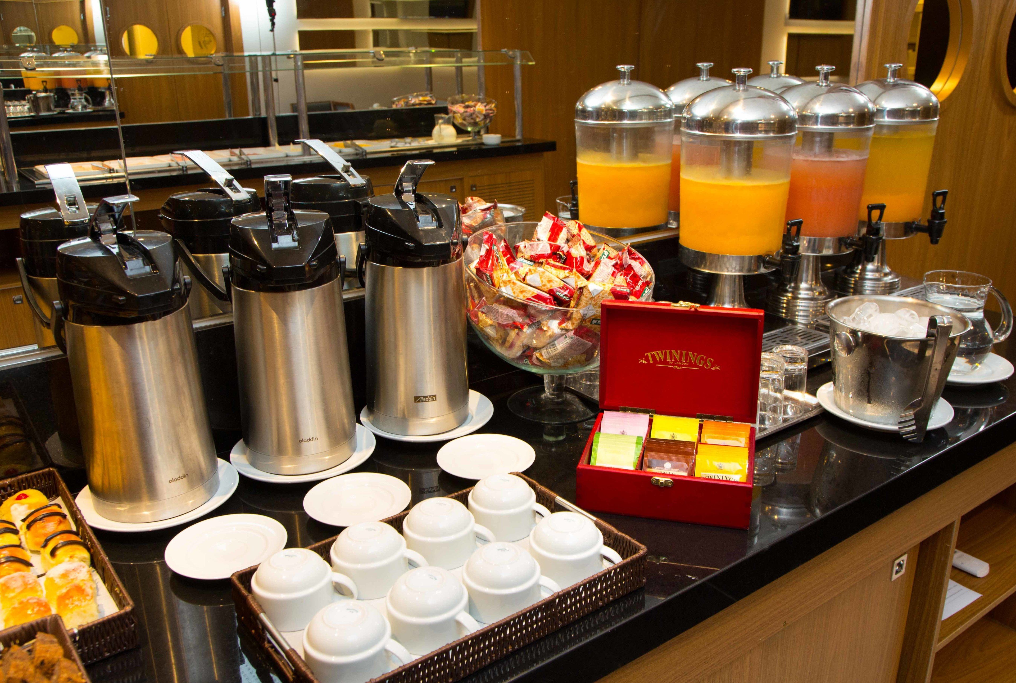 Montaje tipo buffet con cafeteras, dispensadores de jugo y una variedad de alimentos.