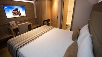 Una habitación de hotel con una cama, televisión, escritorio y zona de ducha.