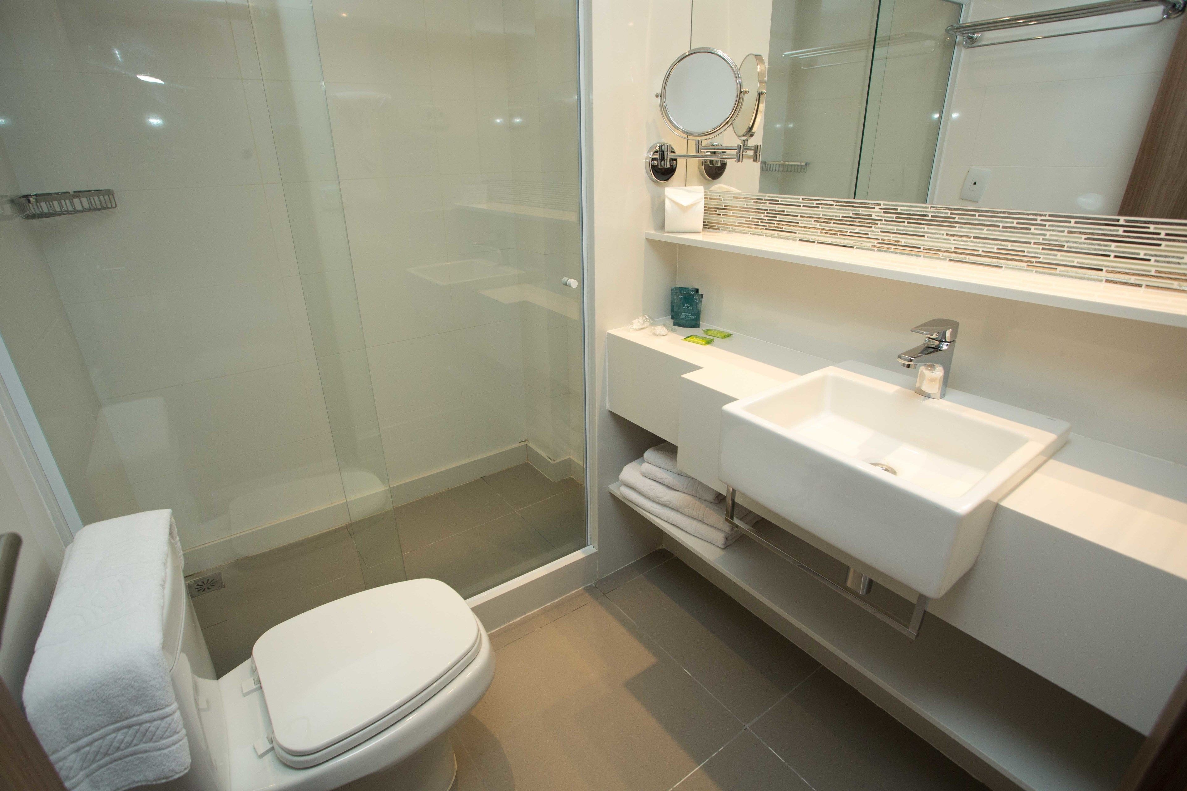 Un baño moderno con cabina de ducha de vidrio, un lavamanos blanco y un inodoro.