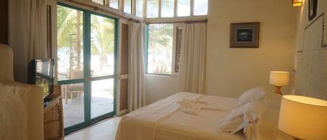 Habitación de hotel con cama, televisión, lámpara y vistas al exterior.