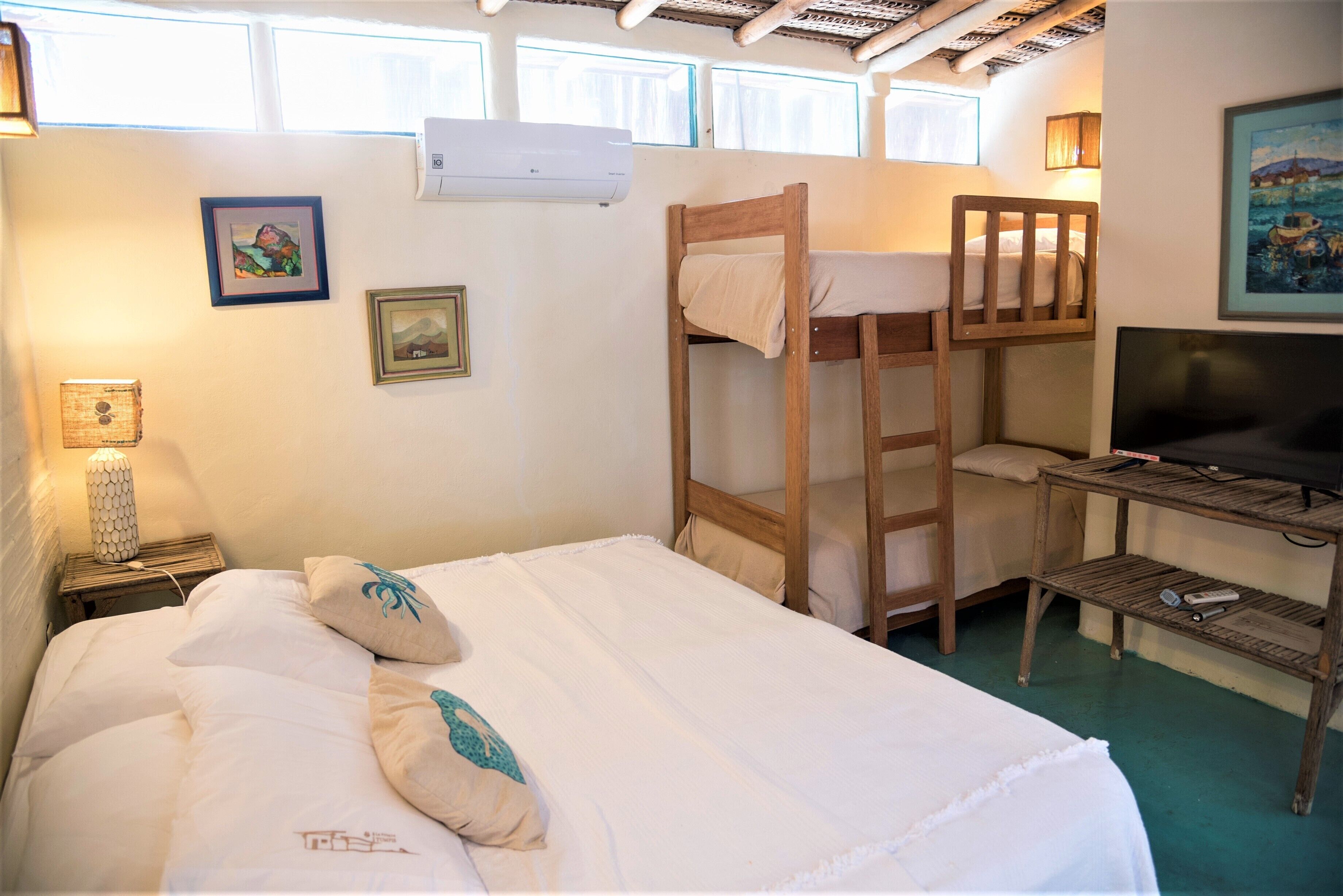 A room with a bunk bed, a desk with a television, and a lamp on a nightstand.