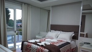 Une chambre d’hôtel avec un lit, une table de chevet, un bureau et une vue sur l’extérieur.