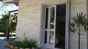 Un bâtiment doté d’une façade en pierre, d’une pergola en bois et d’un chemin de gravier bordé de plantes.