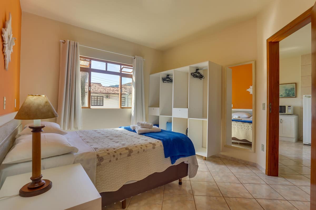 Una camera da letto con un letto, un comodino, una lampada, un armadio e vista all'esterno.