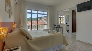 Ein Schlafzimmer mit einem großen Bett, einem Schreibtisch und Blick auf ein Gebäude mit roten Ziegeln.