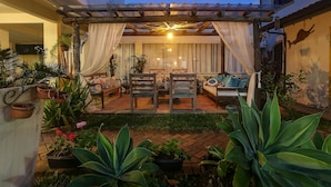 Eine gemütliche Außenpatio mit einem Holz-Pergola, gepolsterten Sitzgelegenheiten und Topfpflanzen.