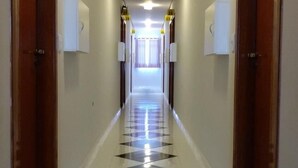 A hotel hallway with numbered doors, a tiled floor, and a bright overhead light. - Lider Hotel (São Bernardo do Campo)