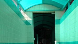 A corridor with tiled walls and a tiled floor, leading to a doorway. - Lider Hotel (São Bernardo do Campo)