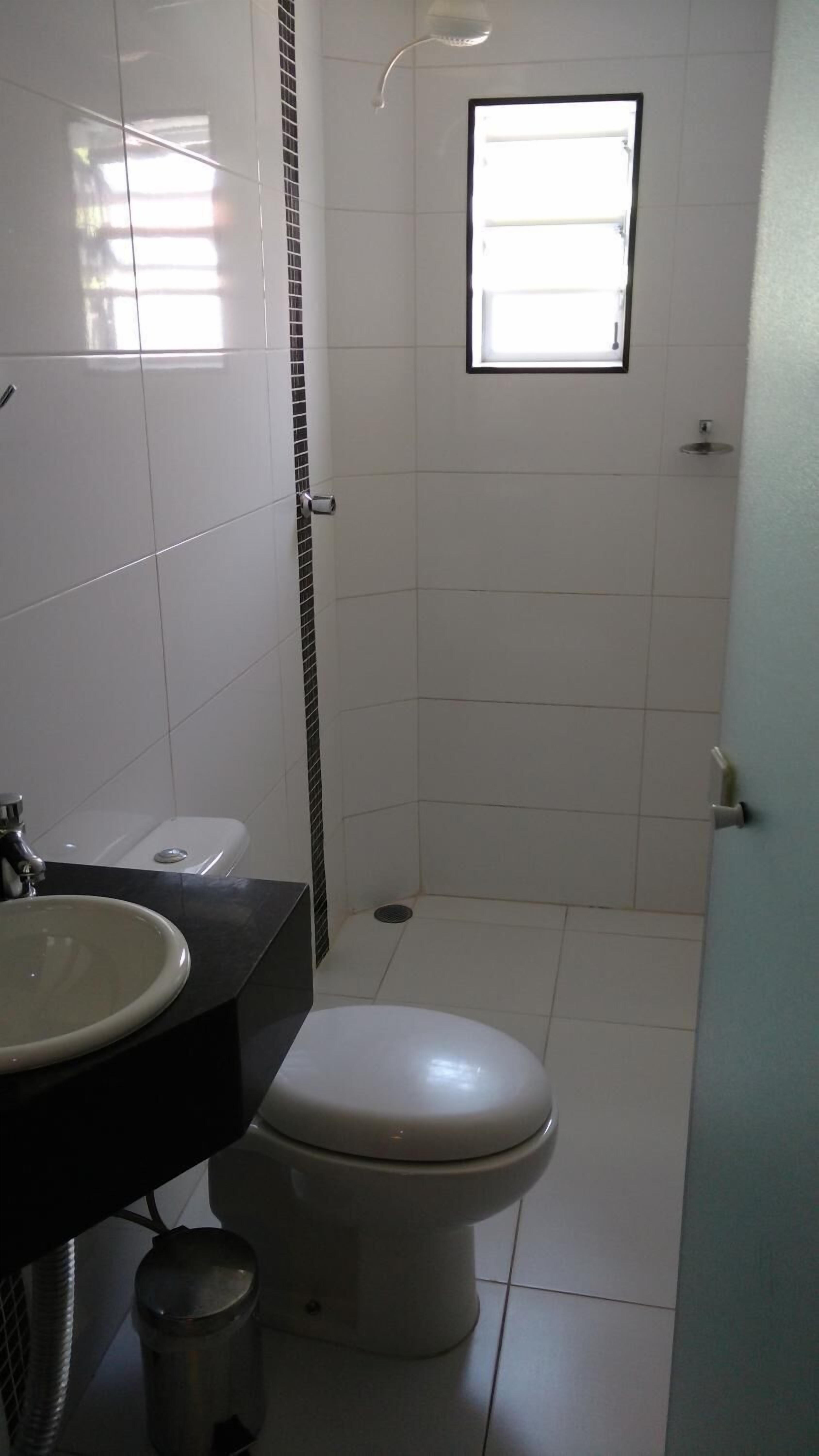 Un baño pequeño y limpio con inodoro, lavamanos y ducha.