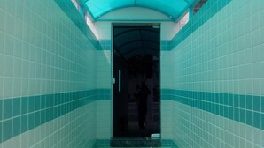 A narrow hallway with teal and white tiled walls and a curved ceiling. - Lider Hotel (São Bernardo do Campo)