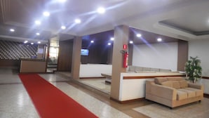 A hotel lobby with a reception desk, a red carpet, a sofa, and a fire extinguisher. - Itaparica Praia Hotel (Vila Velha)