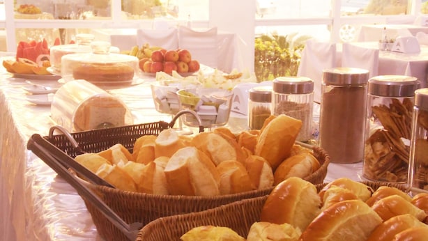A buffet table with various food items including bread, fruits, and condiments. - Itaparica Praia Hotel (Vila Velha)