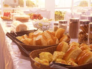Una mesa de buffet con diferentes opciones de comida, incluyendo pan, frutas y salsas.