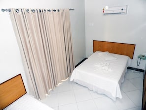 A hotel room with a bed, a bedside table, a telephone, and a wall-mounted air conditioning unit. - Itaparica Praia Hotel (Vila Velha)