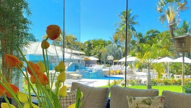 A modern room with a glass wall, a sofa with cushions, and a vase of flowers.